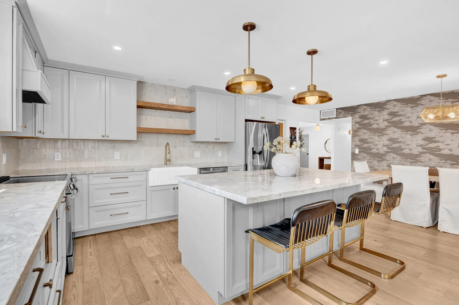 Open kitchen with grey cabinetry, brass hardware and island seating.