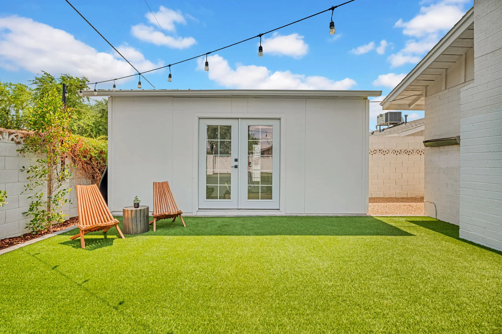 Back yard with turf lawn, string lights and a detached casita.