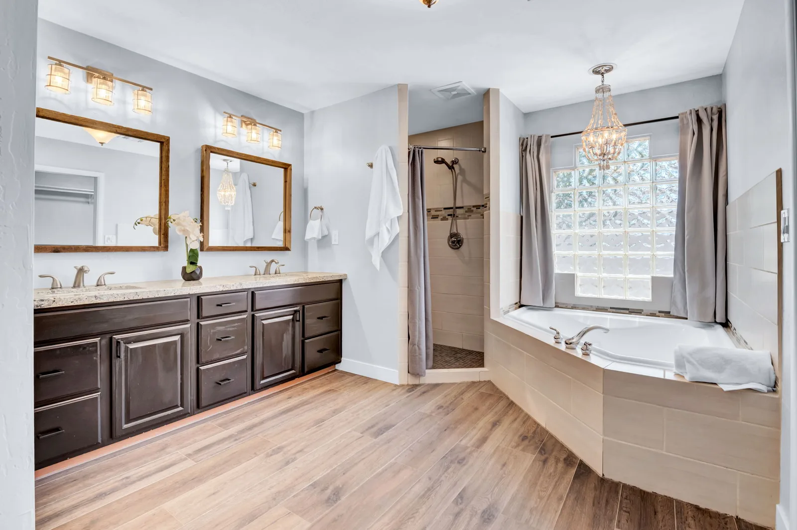 Primary bath with dual vanities, a corner soaking tub and a chandelier.
