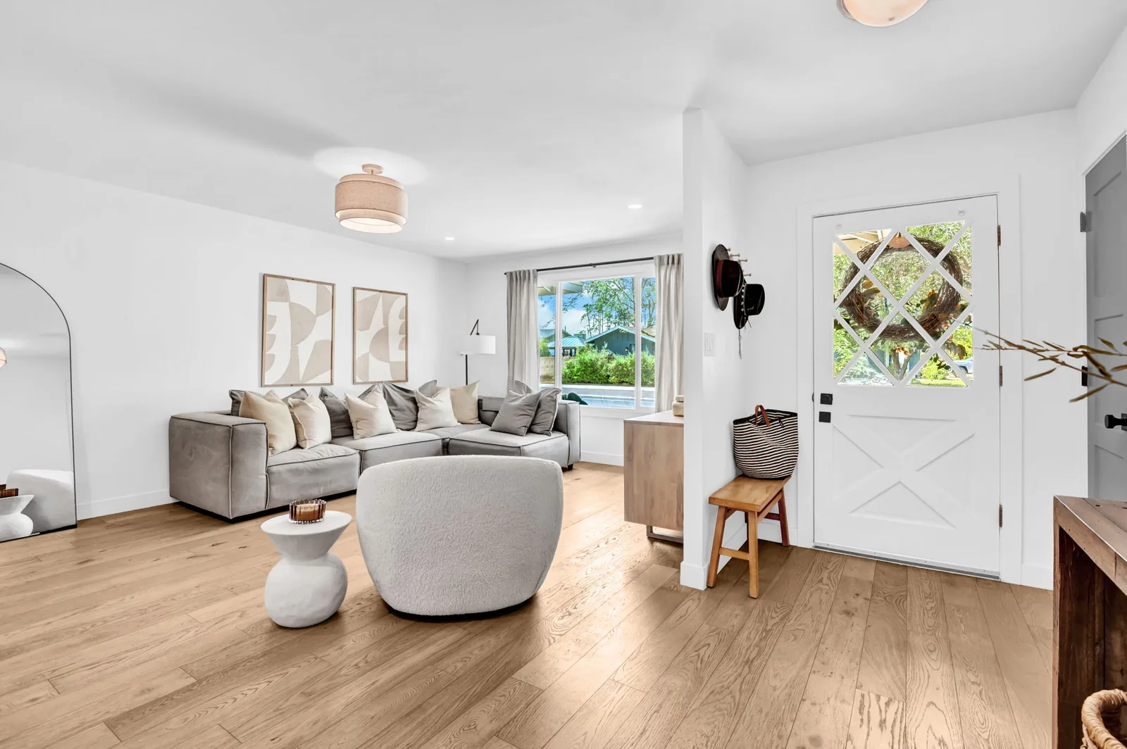 Living room with a curved chair, oak floors and a light-filled entry.