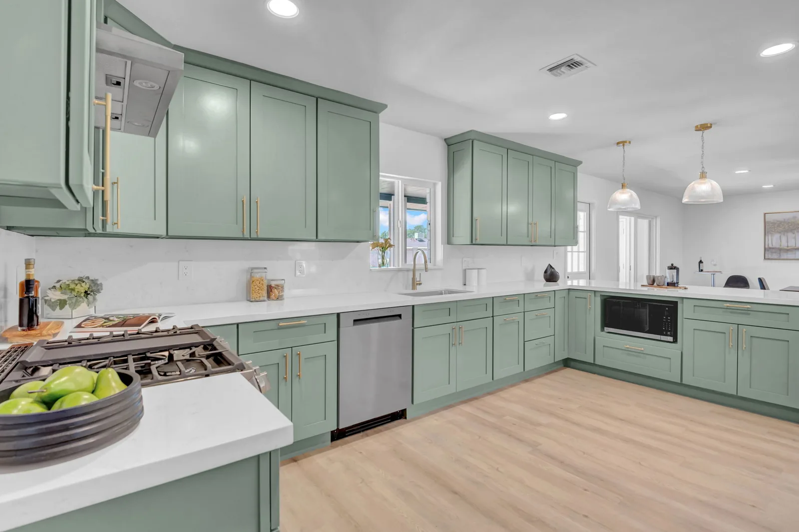 Wide kitchen view with quartz counters, gas range and open sightlines to the dining area.