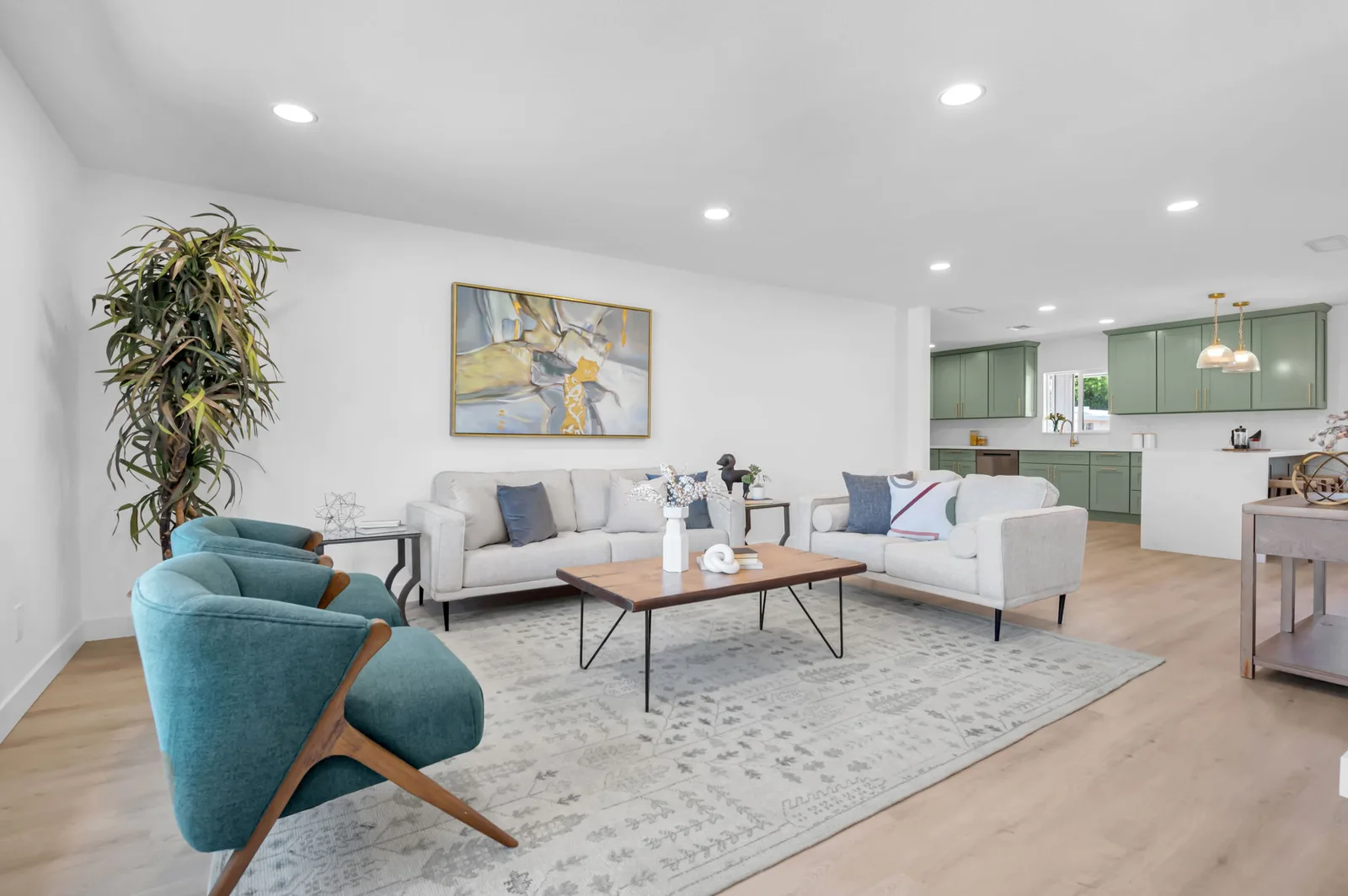 Open living room with light wood floors, teal accent chairs and a wall of natural light.