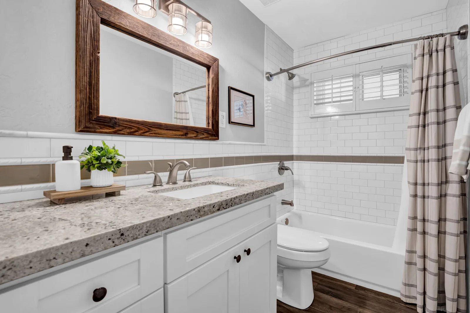 Guest bath with a framed mirror, granite vanity and tub-shower.