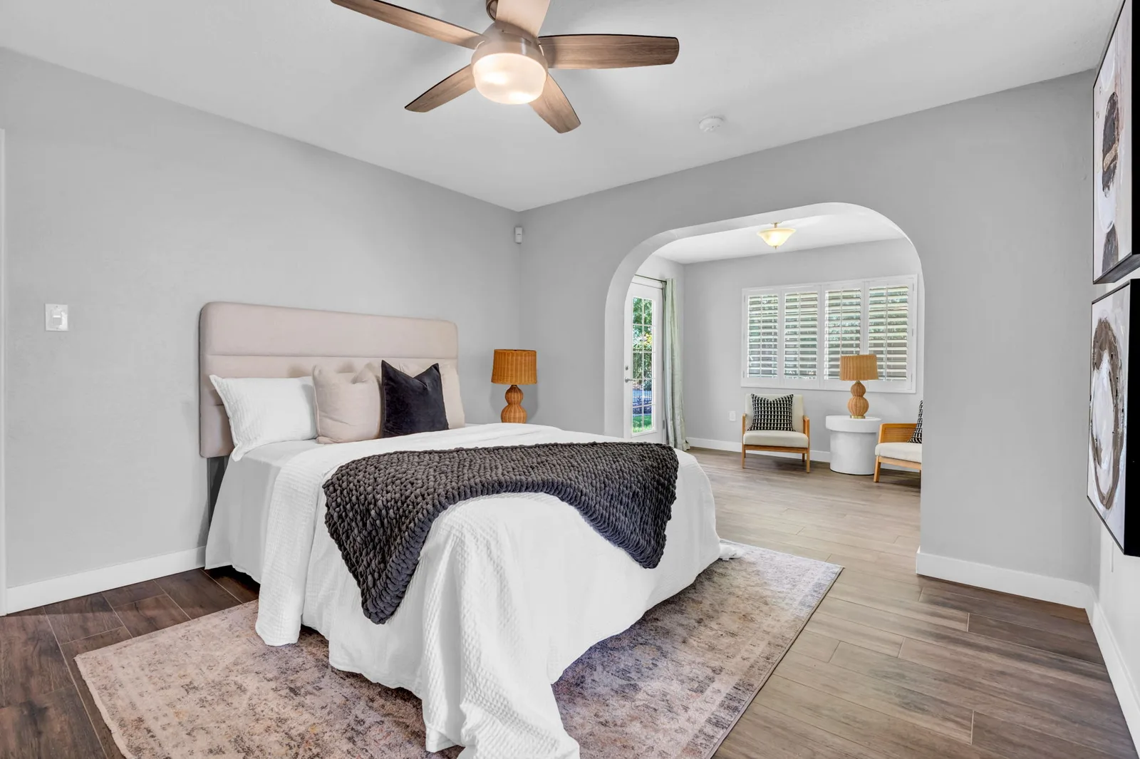 Primary bedroom with a soft throw, ceiling fan and arched doorway.