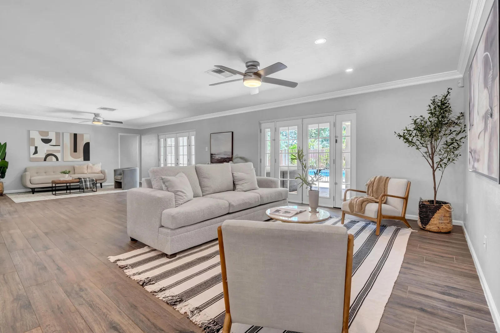 Living room with a low sofa, striped rug and light hardwood floors.