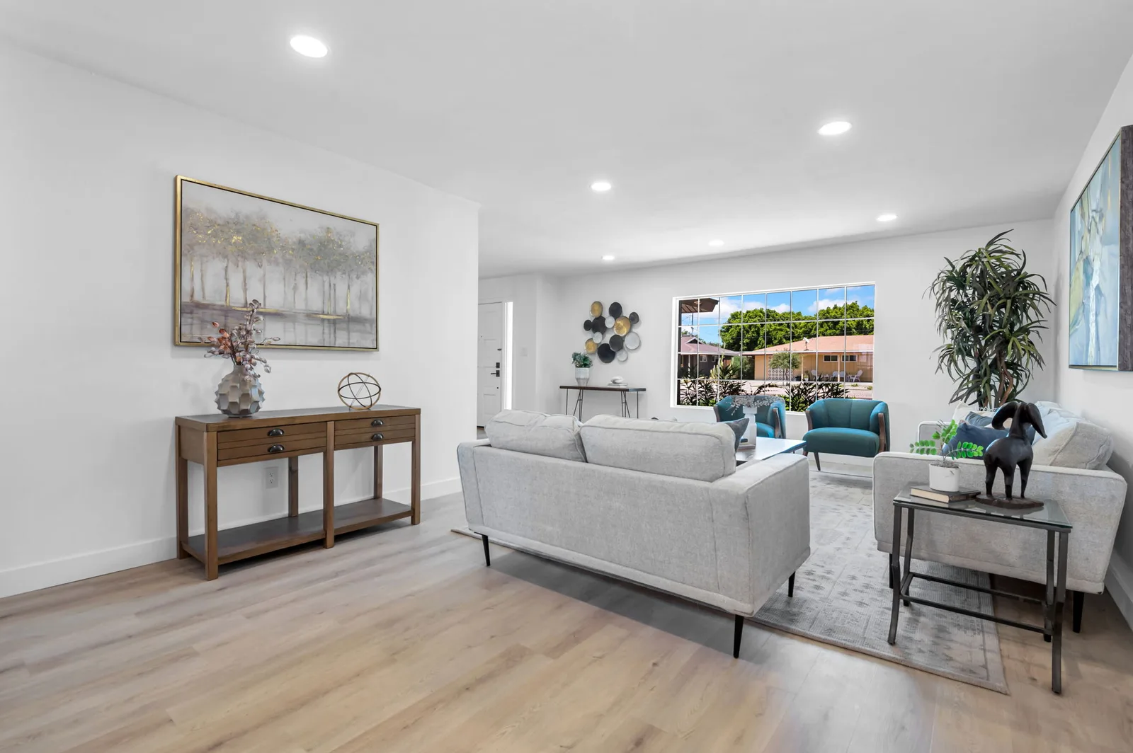 Living room and console styled with art, plants and a low sofa in a remodeled ranch.