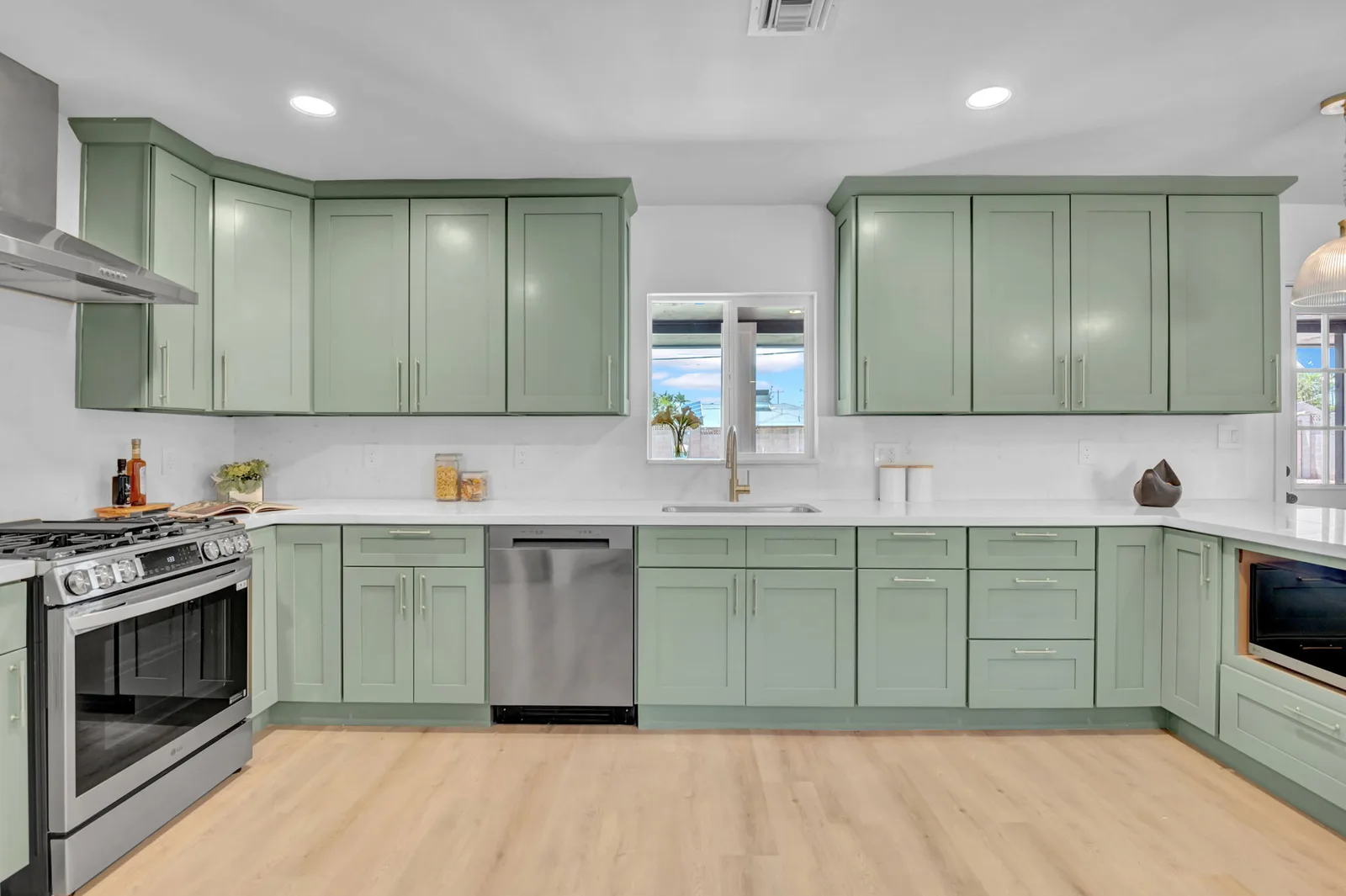 Remodeled kitchen with sage cabinets, stainless range and a window over the sink.