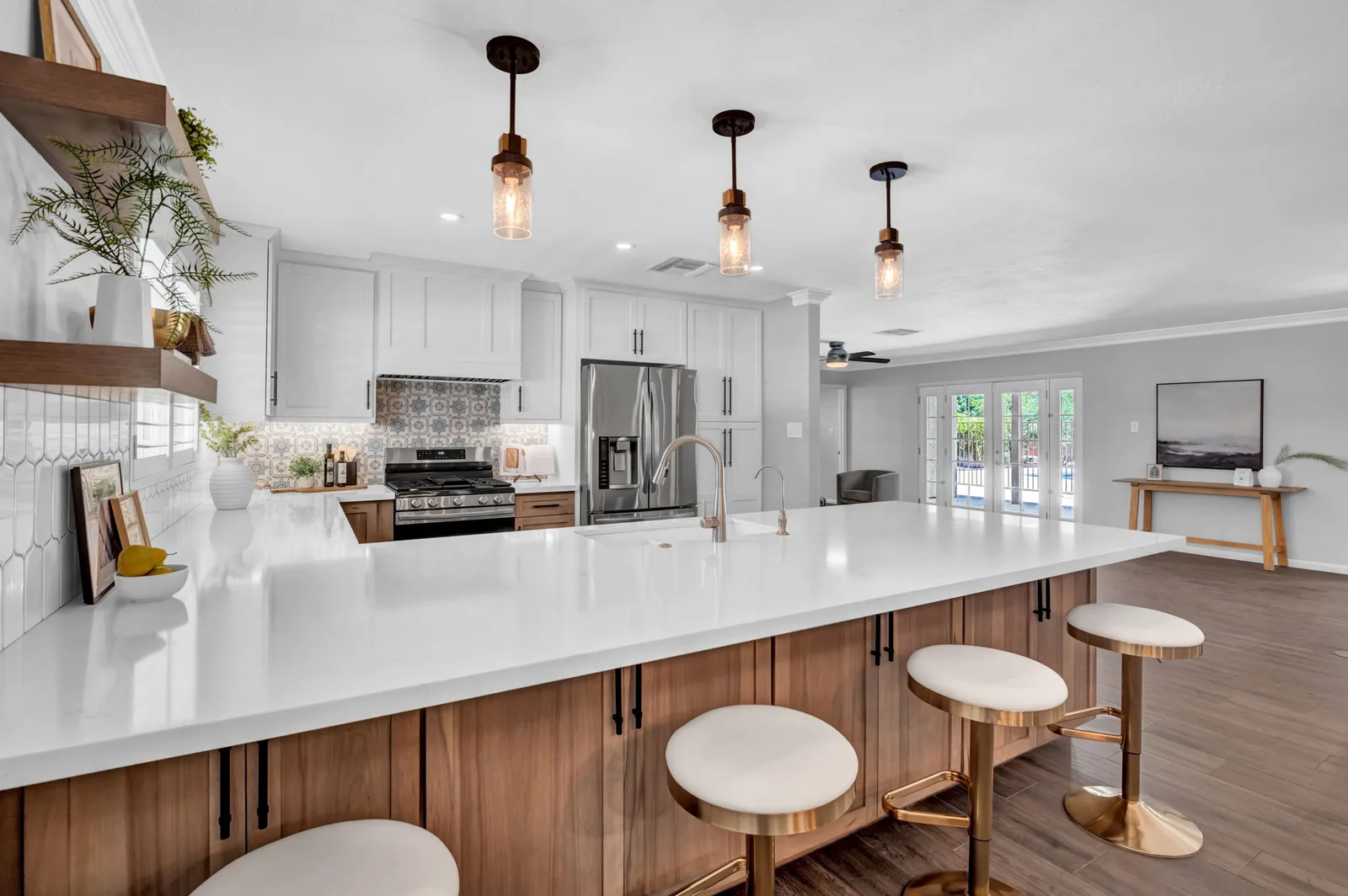 White kitchen with open shelving, stainless refrigerator and island seating.