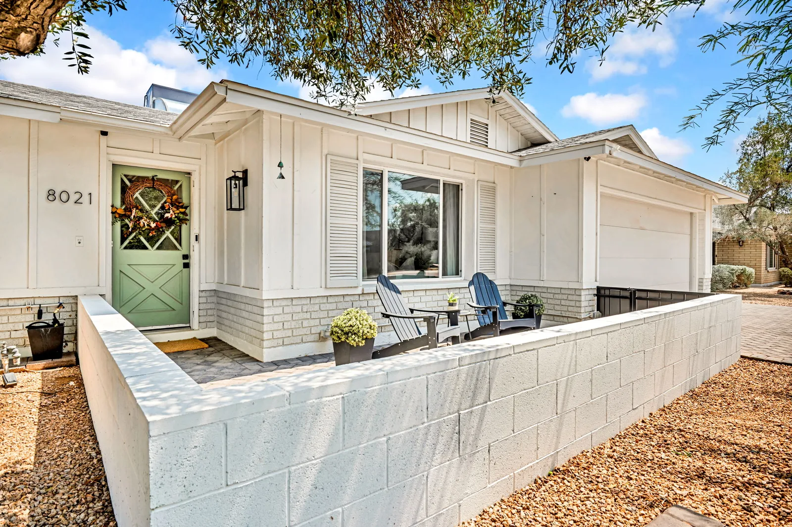 Green front door and porch seating on a remodeled ranch.