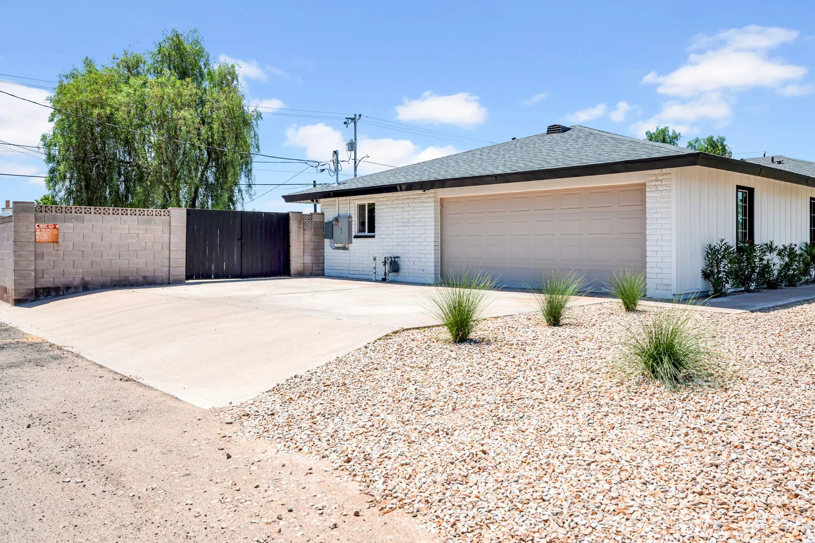 Corner view of a single-story Phoenix home with a mature willow tree over the driveway.